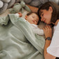 Green blanket with flannel lining draped over a baby for cozy coverage
