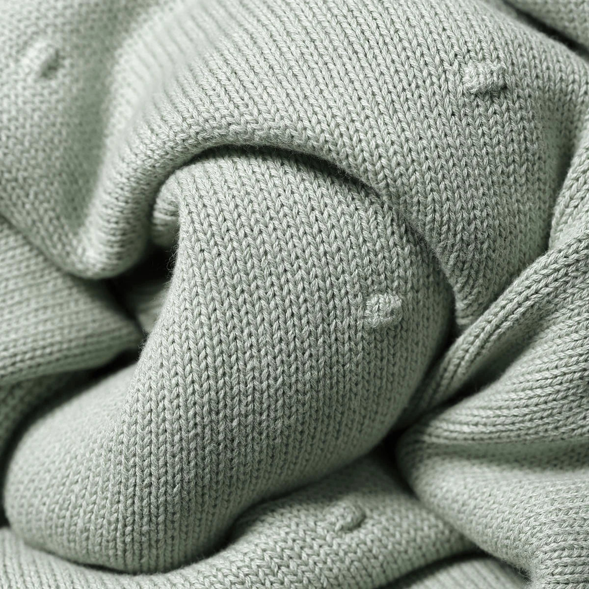 Green knit blanket corner with textured ribbed trim and folded edge