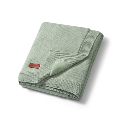 Green cotton blanket with flannel lining, folded with stitched edge and small logo tag