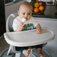 Beige baby food feeder held by an infant with mesh nipple and twist ring