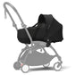 Black newborn carrycot attached to a stroller with light gray frame and wheels.