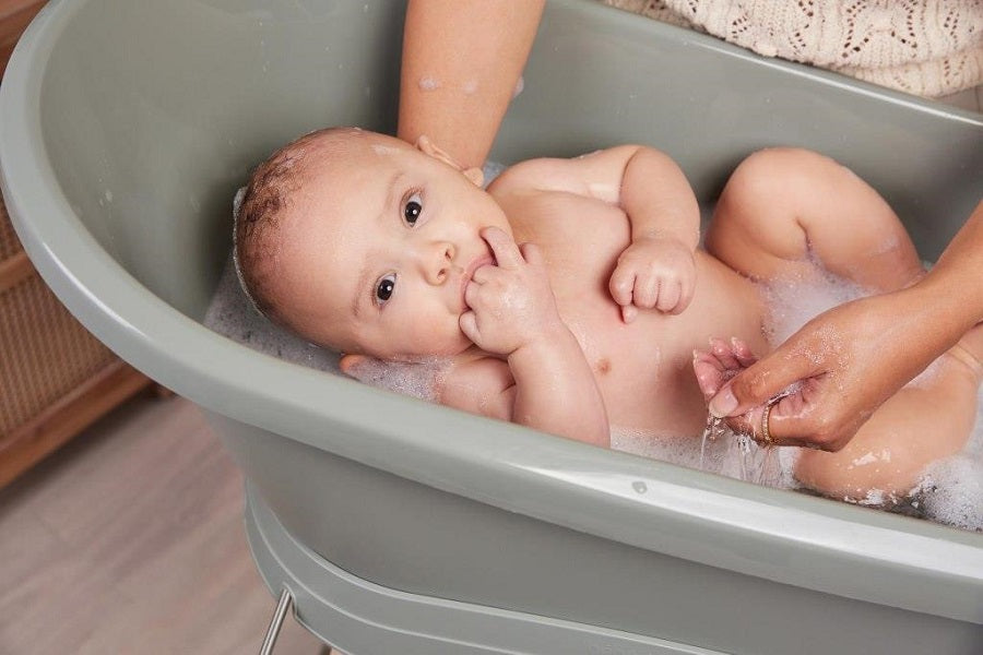 Breeze green baby bath tub on stand with a reclining infant inside
