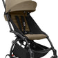 Tan canopy stroller with black frame, front wheels and footrest visible
