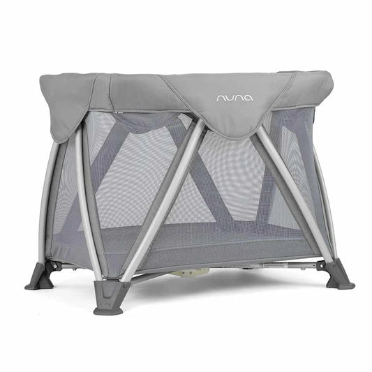 Nuna bedside bassinet with gray canopy, mesh sides, and foldable stand