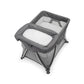 Grey bassinet with padded rails, white inner mattress, angled side view