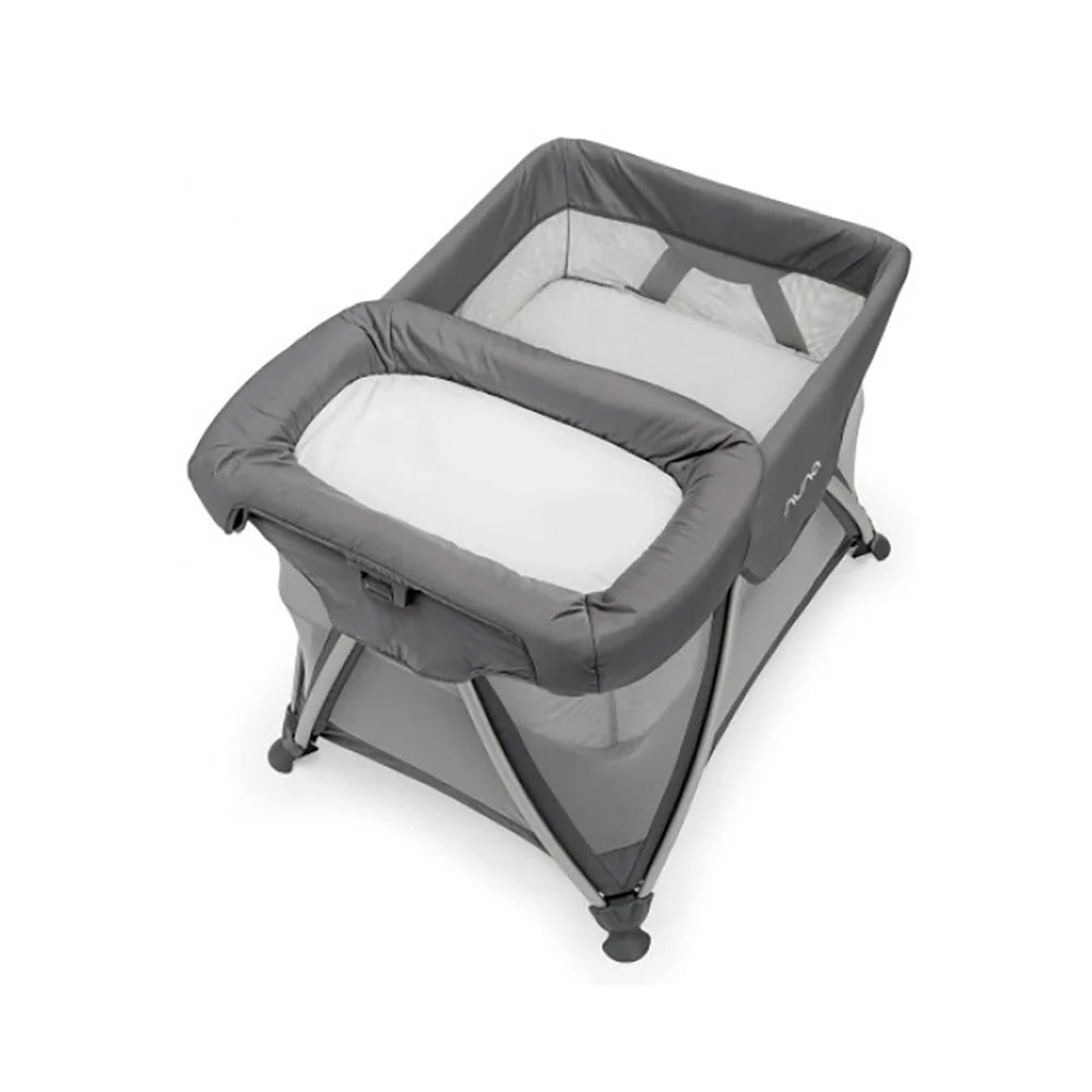 Grey bassinet with padded rails, white inner mattress, angled side view