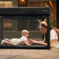 Black playard with mesh sides and canopy, with baby inside