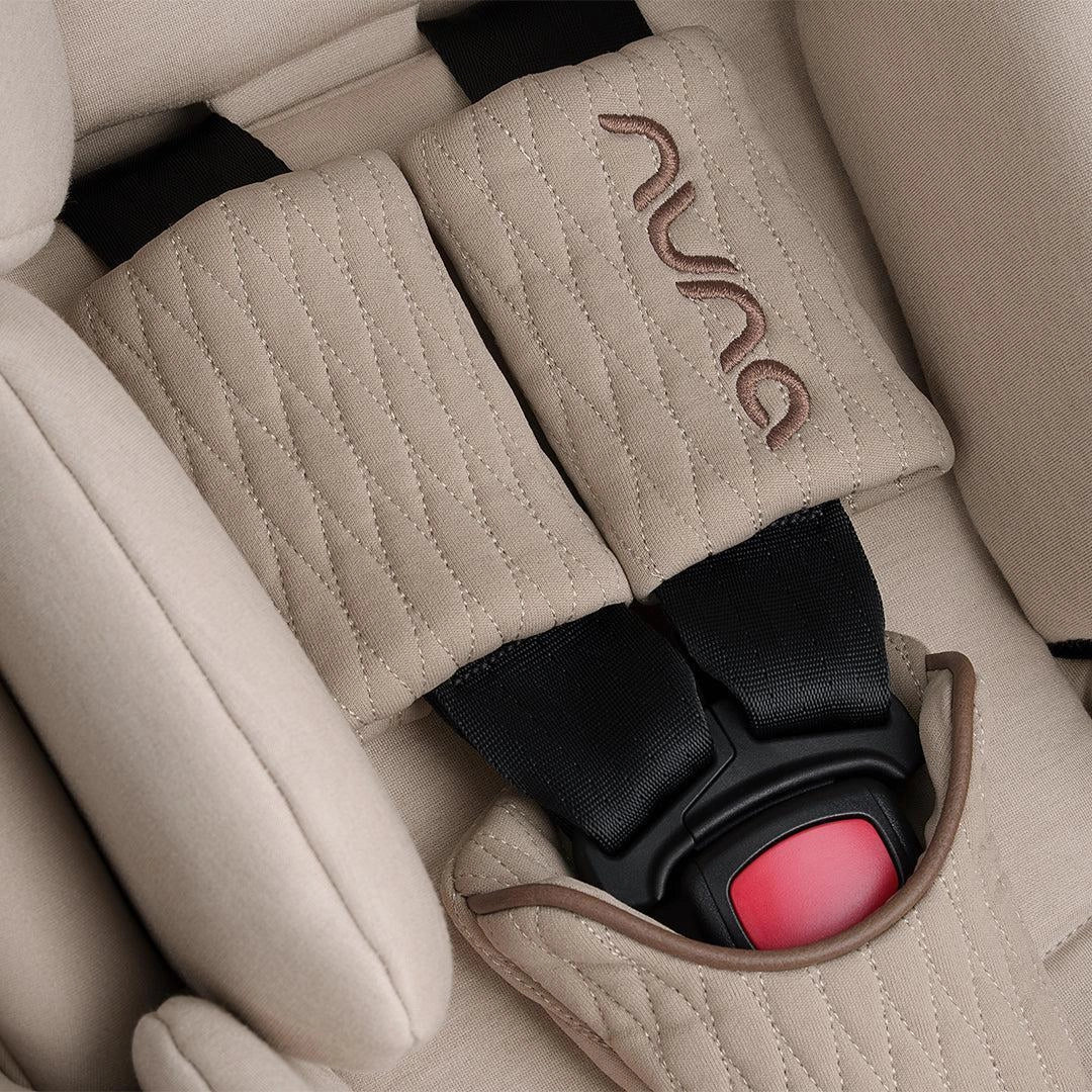 Beige padded car seat harness buckle with quilted straps and logo patch