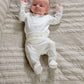 White footed baby bodysuit set with long sleeves and space print, lying on quilt