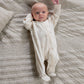 Baby in cream bear-print all-in-one with front zip, long sleeves, open hands