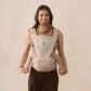 Beige hip seat baby carrier with baby seated in front and padded waist support
