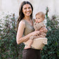 Beige hip seat baby carrier with baby supported on hip and adjustable straps