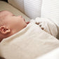 Baby lying in a cream carrycot mattress with quilted bedding
