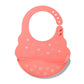 Silicone baby bib in coral pink with small heart pattern and snap-adjustable strap